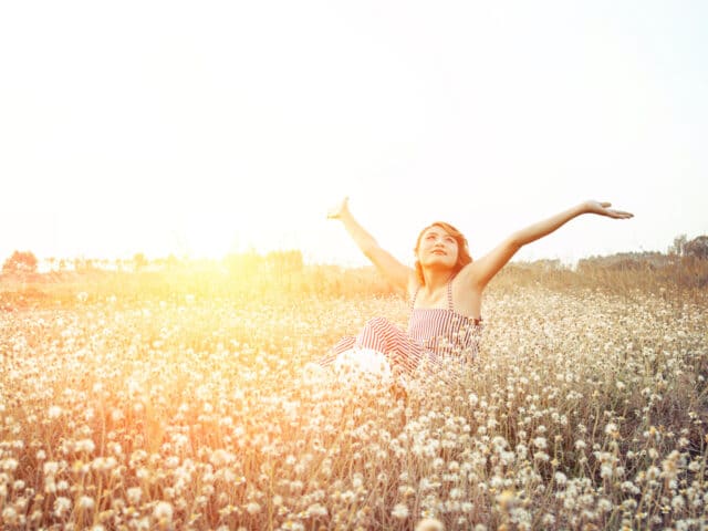 Woman in a field with arms raised